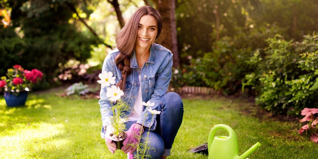 Happy young woman planting flowers in the garden