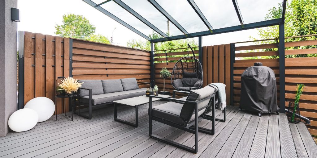 patio-privacy-ideas garden-gate Outdoor terrace with a comfortable outdoor sofa and chairs next to a private building.