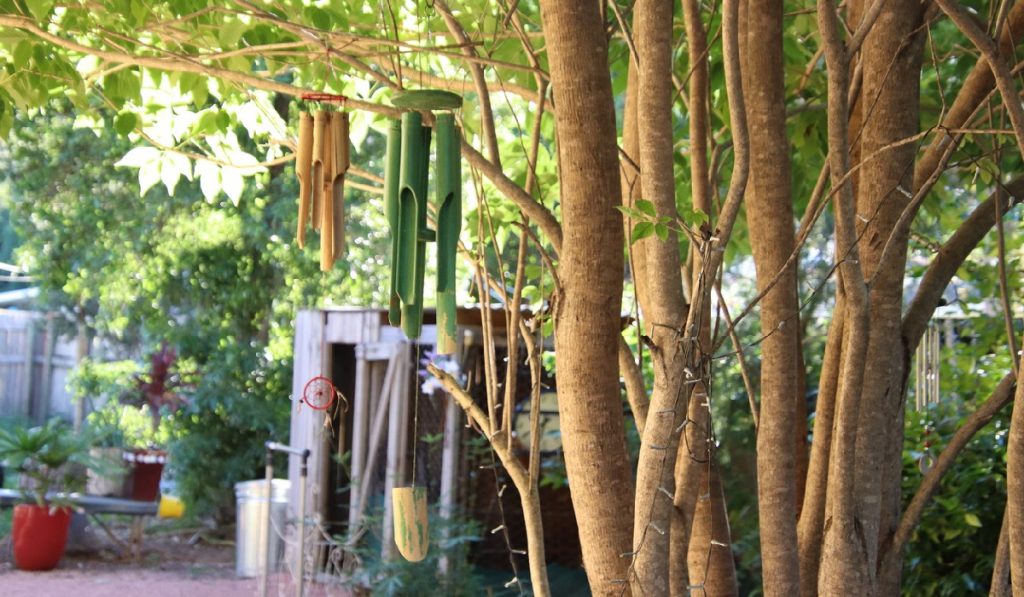 Focus on bamboo garden chimes hanging from tree in backyard