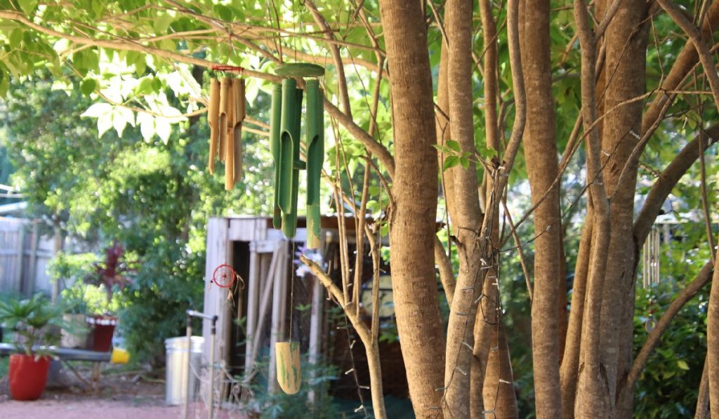 summer-scents-in-garden garden-gate Focus on bamboo garden chimes hanging from tree in backyard