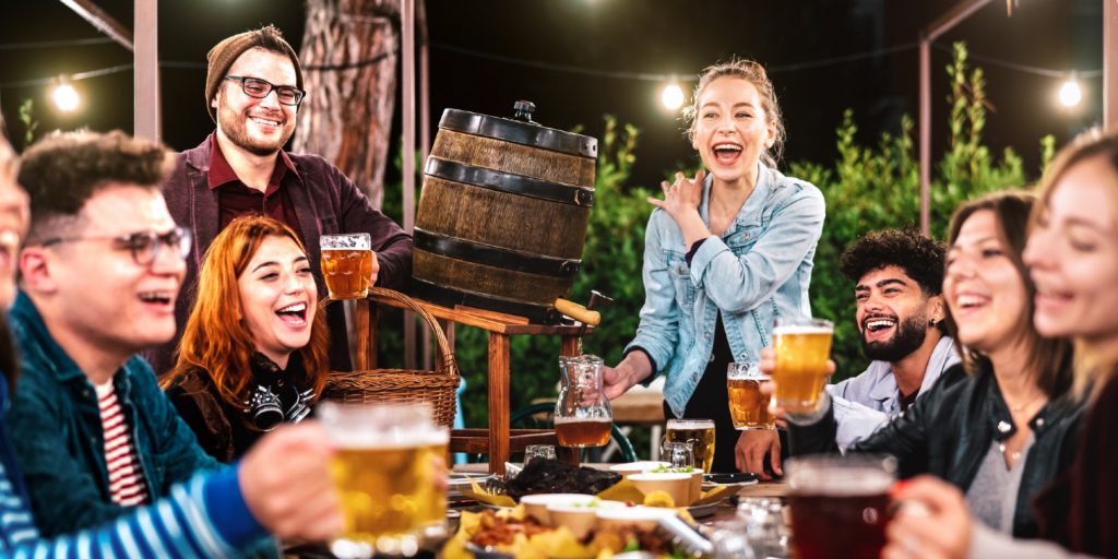 Happy men and women having fun drinking out at beer garden