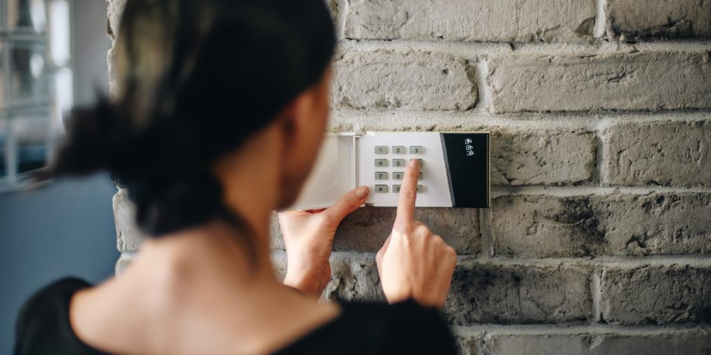 Young woman entering security pin on home alarm keypad
