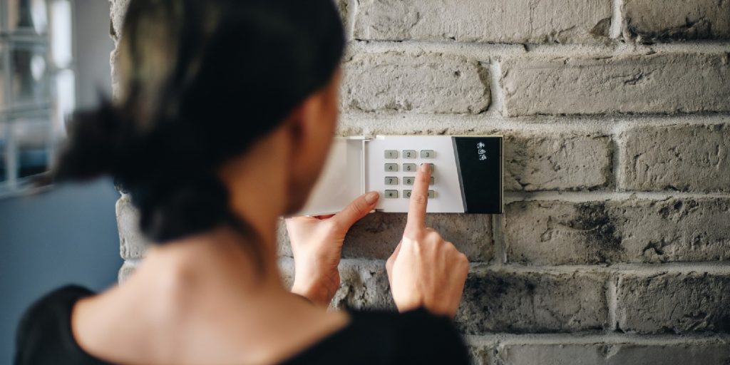 home-safety garden-gate Young woman entering security pin on home alarm keypad