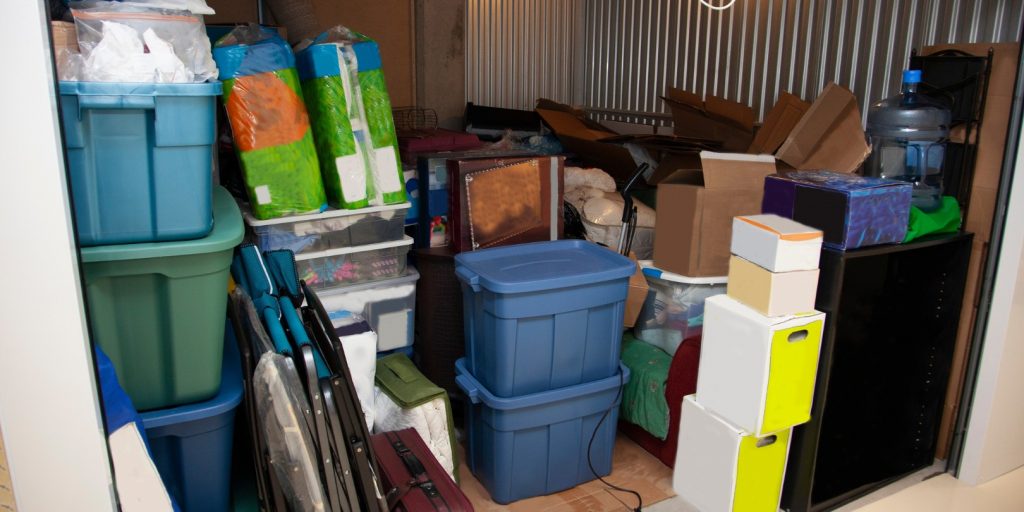 A storage unit full of boxes and plastic tubs