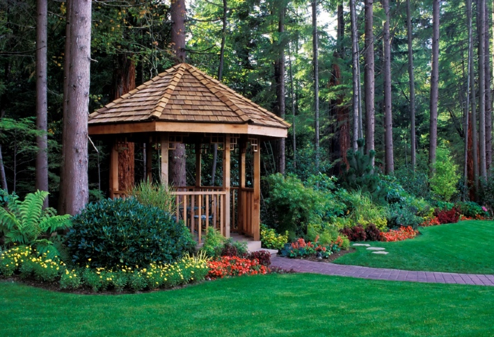 A cozy pergola amongst trees and other greenery.