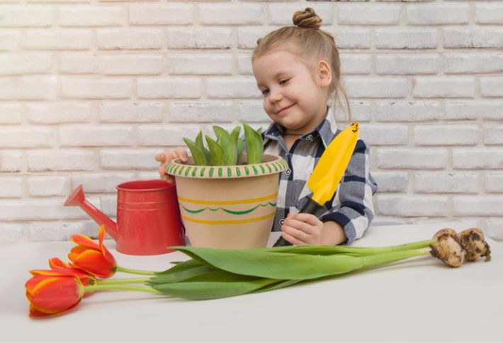 A little girl potting a plant using her kids' gardening set.