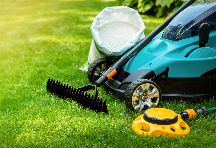 Image of a lawn aerator, lawnmower, bag and more on a lawn.